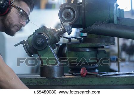 Stock Image - Man working in grinding workshop. Fotosearch