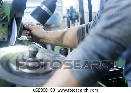 Stock Image - Man working in grinding workshop. Fotosearch
