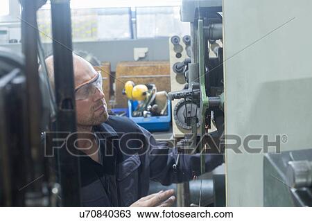 Stock Image - Man working in grinding workshop. Fotosearch