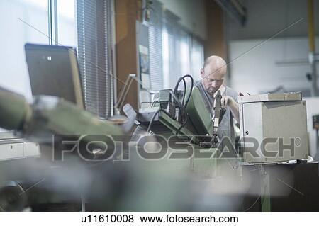 Stock Photo - Man working in grinding workshop. Fotosearch