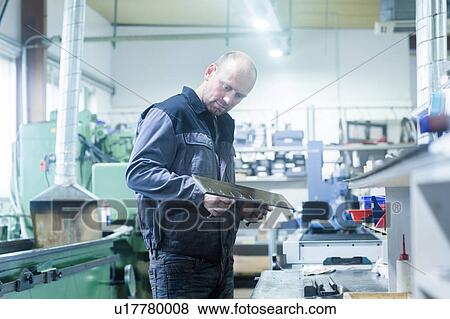 Stock Photo - Man working in grinding workshop. Fotosearch
