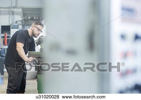 Stock Photo - Man working in grinding workshop. Fotosearch