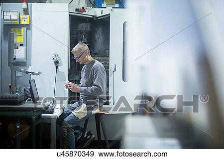 Stock Photo - Man working in grinding workshop. Fotosearch