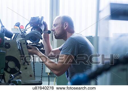 Stock Photo - Man working in grinding workshop. Fotosearch