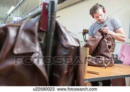 Stock Image - Man working in leather jacket manufacturers. Fotosearch