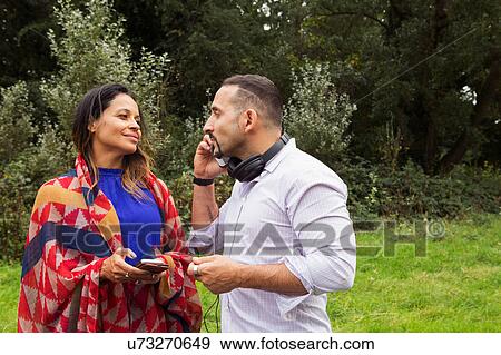 Stock Photo - Mature couple outdoors, using smartphones. Fotosearch