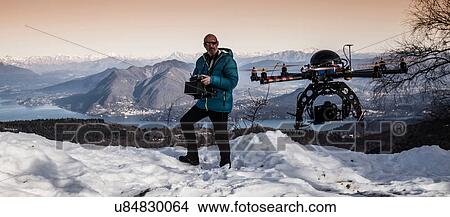Picture - Mature man preparing to fly drone, Stresa, Piedmont, Italy. Fotosearch