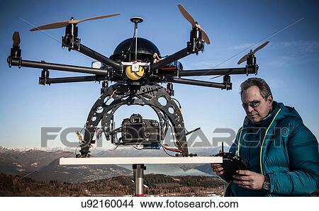 Picture - Mature man preparing to fly drone, Stresa, Piedmont, Italy. Fotosearch