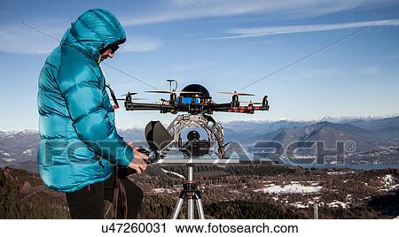 Stock Image - Mature man preparing to fly drone, Stresa, Piedmont, Italy. Fotosearch