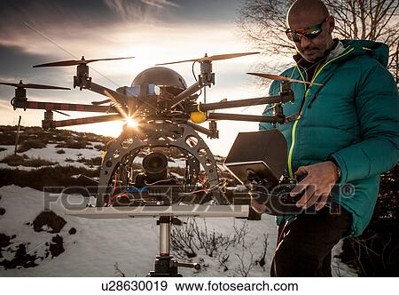 Stock Photo - Mature man preparing to fly drone, Stresa, Piedmont, Italy. Fotosearch