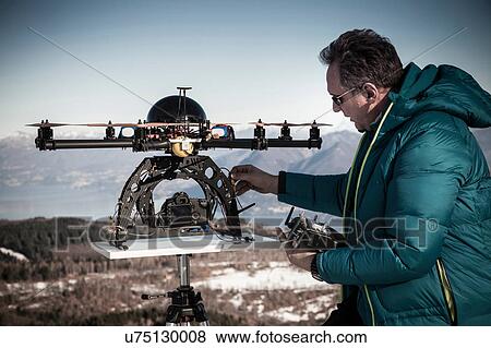 Stock Photo - Mature man preparing to fly drone, Stresa, Piedmont, Italy. Fotosearch