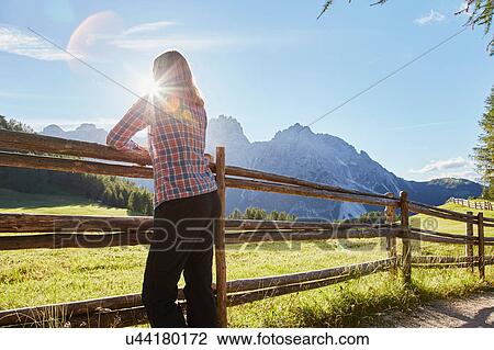 Mature woman leaning against fence looking out at sunlit Dolomites, Sexten, South Tyrol, Italy View Large Photo Image Stock Image - Mature woman leaning against fence looking out at sunlit Dolomites, Sexten, South Tyrol, Italy. Fotosearch