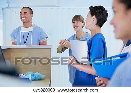 Medical staff chatting at nurses station in hospital View Large Photo Image Stock Photo - Medical staff chatting at nurses station in hospital. Fotosearch