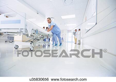 Medics urgently pushing hospital bed along corridor View Large Photo Image Stock Photograph - Medics urgently pushing hospital bed along corridor. Fotosearch