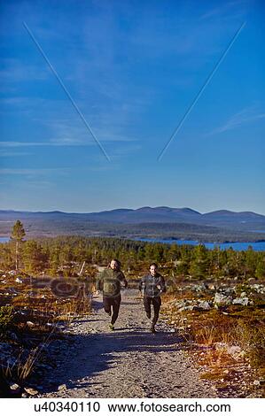 Stock Image - Men running on gravel road, Sarkitunturi, Lapland, Finland. Fotosearch