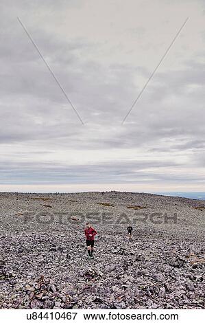 Stock Photo - Men running on rocky cliff top, Kesankitunturi, Lapland, Finland. Fotosearch