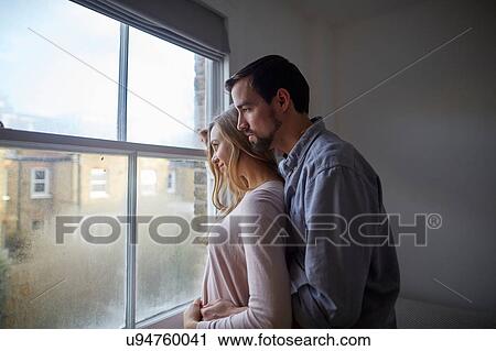 Mid adult couple gazing out through bedroom window View Large Photo Image Stock Image - Mid adult couple gazing out through bedroom window. Fotosearch