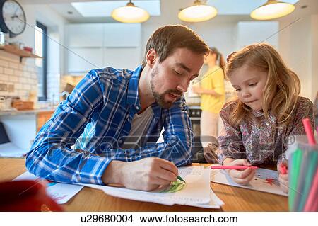 Mid adult man and daughter colouring at table in kitchen View Large Photo Image Picture - Mid adult man and daughter colouring at table in kitchen. Fotosearch