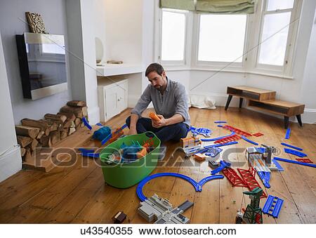 Stock Photography - Mid adult man contemplating toys scattered in living room. Fotosearch