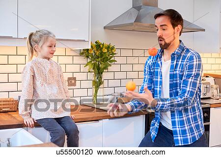 Mid adult man juggling fruit for daughter in kitchen View Large Photo Image Stock Image - Mid adult man juggling fruit for daughter in kitchen. Fotosearch