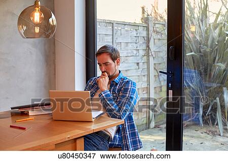 Mid adult man reading laptop update at dining table View Large Photo Image Stock Photo - Mid adult man reading laptop update at dining table. Fotosearch