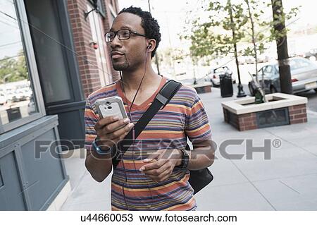 Stock Image - Mid adult man with phone in street. Fotosearch