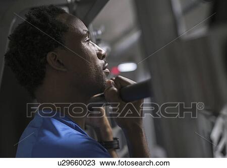 Stock Image - Mid adult man working out in gym. Fotosearch