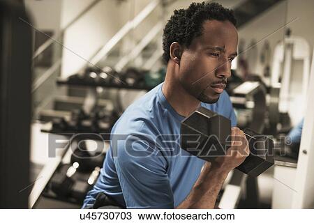 Stock Image - Mid adult man working out in gym. Fotosearch