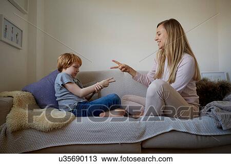 Mid adult woman and son playing rock-paper-scissors on sofa View Large Photo Image Stock Image - Mid adult woman and son playing rock-paper-scissors on sofa. Fotosearch