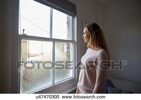 Mid adult woman gazing out through bedroom window View Large Photo Image Stock Image - Mid adult woman gazing out through bedroom window. Fotosearch
