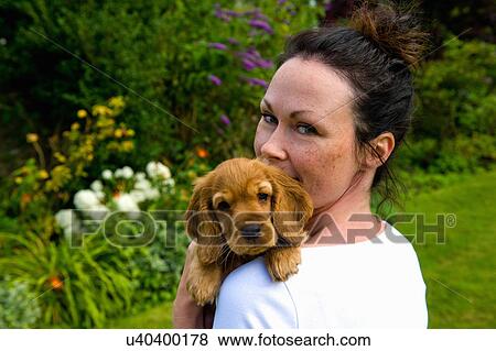 Stock Photo - Mid adult woman holding pet dog, rear view. Fotosearch