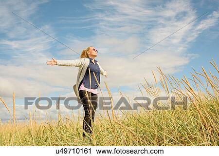 Mid adult woman in wheat field, arms outstretched, low angle view View Large Photo Image Stock Image - Mid adult woman in wheat field, arms outstretched, low angle view. Fotosearch