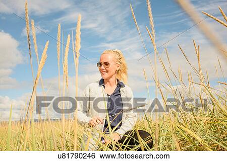 Mid adult woman in wheat field, holding ear of wheat View Large Photo Image Stock Photograph - Mid adult woman in wheat field, holding ear of wheat. Fotosearch