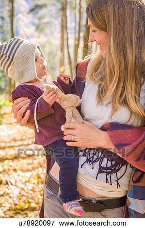 Stock Photo - Mother and baby with cuddly toy in forest. Fotosearch