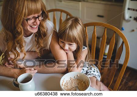 Mother and daughter cuddling at breakfast table View Large Photo Image Stock Photo - Mother and daughter cuddling at breakfast table. Fotosearch