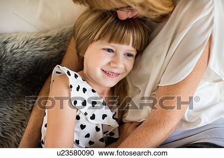 Stock Image - Mother and daughter cuddling in bed. Fotosearch