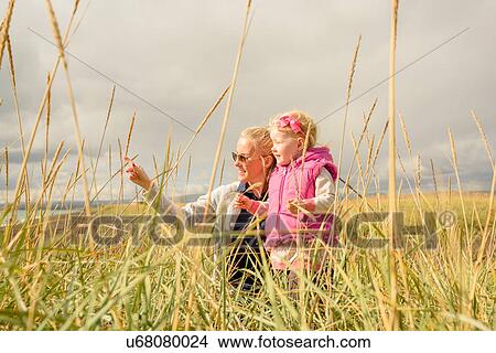 Mother and daughter in field, looking at view View Large Photo Image Picture - Mother and daughter in field, looking at view. Fotosearch