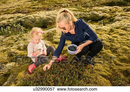 Mother and daughter outdoors, picking blueberries View Large Photo Image Stock Photo - Mother and daughter outdoors, picking blueberries. Fotosearch