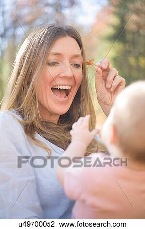 Stock Image - Mother and daughter playing with leaf smiling. Fotosearch