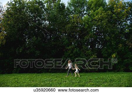 Stock Image - Mother and daughter walking in the park. Fotosearch