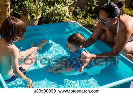 Mother and sons playing in inflatable pool on summer day View Large Photo Image Stock Photo - Mother and sons playing in inflatable pool on summer day. Fotosearch