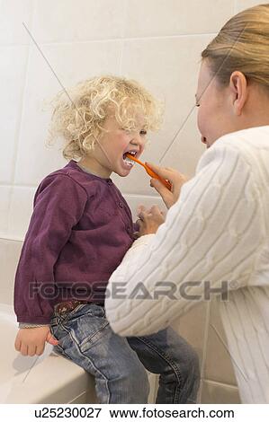 Stock Photo - Mother brushing daughter's teeth (4-5) in bathroom. Fotosearch