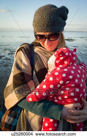 Mother by sea holding sleeping baby girl View Large Photo Image Picture - Mother by sea holding sleeping baby girl. Fotosearch