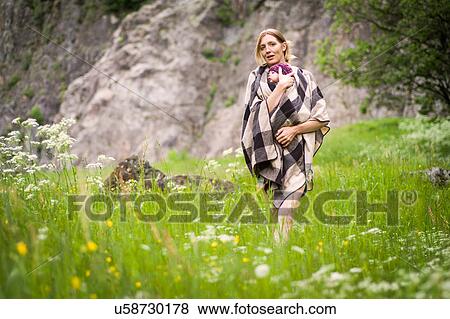 Stock Photo - Mother carrying baby girl through meadow. Fotosearch