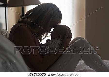 Stock Image - Mother holding son (0-1 months) in bedroom. Fotosearch