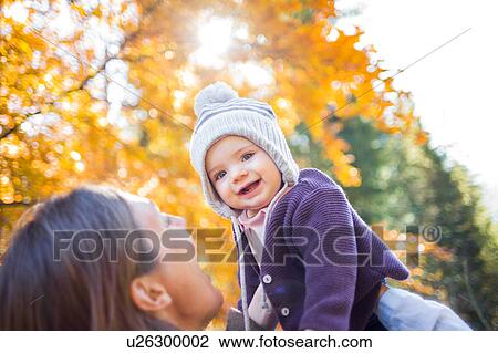 Stock Image - Mother holding up smiling baby girl. Fotosearch