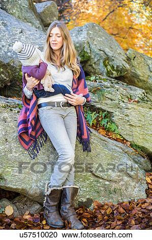 Mother leaning against rocks holding baby girl View Large Photo Image Stock Image - Mother leaning against rocks holding baby girl. Fotosearch