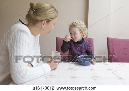 Mother looking at daughter (4-5) eating breakfast View Large Photo Image Stock Image - Mother looking at daughter (4-5) eating breakfast. Fotosearch