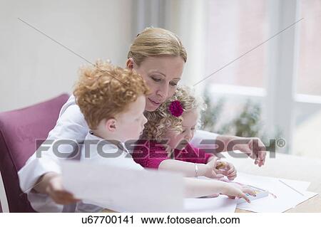 Stock Image - Mother looking at drawings with son (8-9) and daughter (4-5). Fotosearch