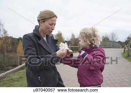 Stock Photo - Mother putting glove on daughter's hand (4-5). Fotosearch